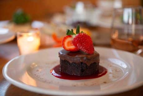 Double Chocolate Flourless cake on a white plate with a strawberry for Valentines Day Dinner at Frothy Monkey.